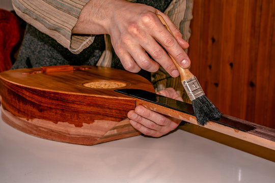 male luthier putting french polish - shellac on the instrument with brush, an oriental musical instrument, lavta. 