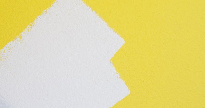 Painting using hand roller, painting white paint over yellow wall close-up, room renovation with fresh color, 4k 