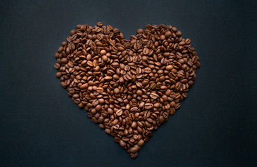 Heart of roasted, fresh coffee beans on a black background. Love. Still life. Horizontal photo in good quality.