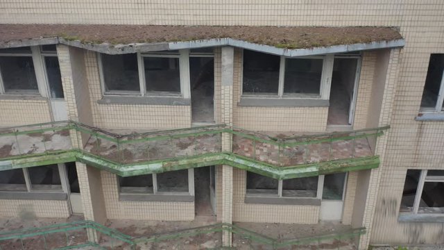 Aerial side view of an abandoned hotel (motel or vacation retreat) with broken windows on the balconies. 