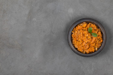 Stewed cabbage with carrots and onions in a wooden bowl in rustic style top view