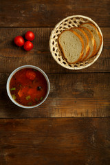 a plate of Italian tomato soup with potatoes and mushrooms and bread on a table from raw boards.