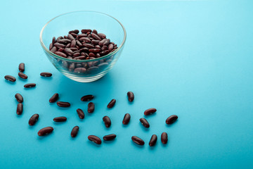 Glass jar with red beans on a blue background.