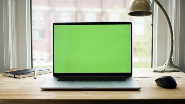 Green screen laptop computer sitting on a home work desk next to a desk lamp. Footage shot with RED, available in 4K and HD. Download the preview for free. 