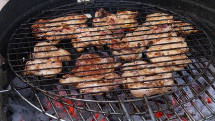Tasty and marinated Chicken meat fried on a barbecue grill at backyard outdoor.