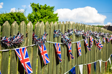 Union Jack bunting on a fence row, many flags in row on a string, triangular flags, front of garden...