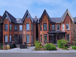 Fototapeta na wymiar Residential street with narrow brick Victorian style houses with gables