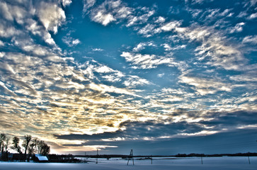 Snowy meadow field with cloudy sky in sunrise