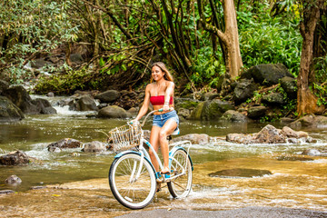 A young girl riding her bicycle on a rural road in a tropical area of Kauai in Hawaii. 