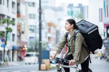 自転車で荷物の配送を行う若い女性