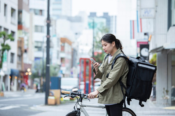 Fototapeta na wymiar 自転車で荷物の配送を行う若い女性