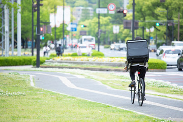 Fototapeta premium 自転車で荷物の配送を行う若い女性