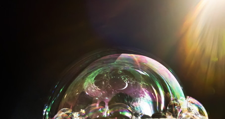 Colorful Bubble soap on a black background. Looks like a planet with sunlight