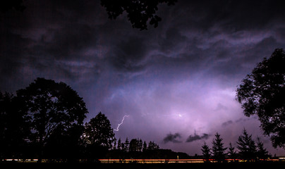 Lightning in dark night sky with car light beams