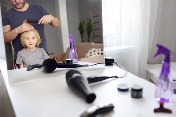 Preschooler boy gets haircut at home during quarantine. Hair cutting for kids by parents while...