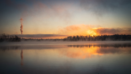 Sunrise over a tree line and calm water at Lake Ontelaunee in Pennsylvania