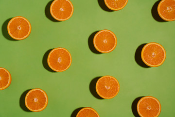 Fruit pattern with sliced oranges on green paper background. Top view. Summer concept