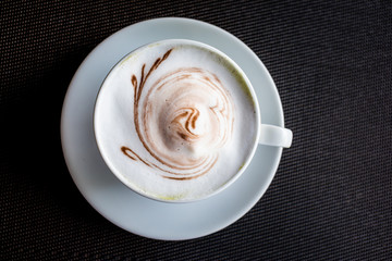 A cup of hot art coffee on black background.