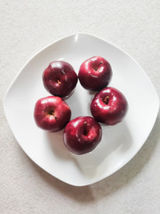 Apples on a white plate. Apples are rich in vitamin C, vitamin B6 and vitamin B1. One apple contains moderate (approximately 180 grams) contains 8.4 mg of vitamin C. Top View Shot. Selective Focus.
