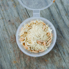 Plastic container with sawdust and maggots for fishing on a wooden pier. Preparing for fishing. Close up.