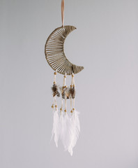 Dreamcatcher in the shape of a Crescent moon on a gray background. Interior decoration. Native American Dreamcatcher.