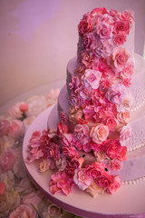 White wedding cake with pink roses around it