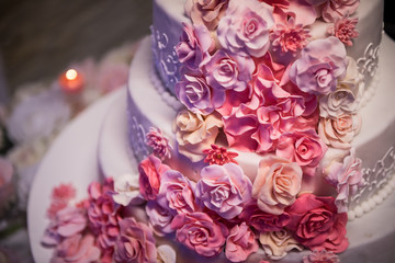 White wedding cake with pink roses around it