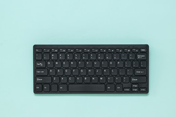 Wireless black keyboard on a light blue background. - obrazy, fototapety, plakaty