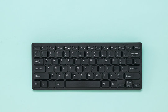 Wireless black keyboard on a light blue background.