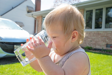 Toddler drinking water in her backyard