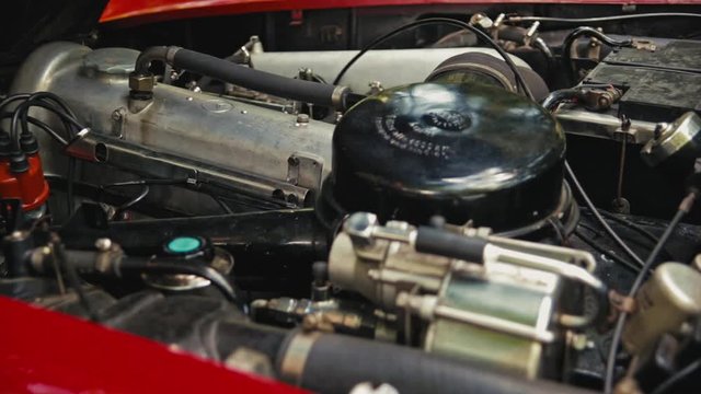 Start of a red Old-Timer car. Close shot of a old engine starting. Red Mercedes SL cabriolet in the woods on a sunny day.