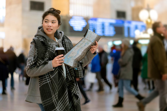 attractive beautiful asian female woman travel alone enjoy sight seeing and look for direction in grand central terminal with crowd people blur background rush hour moment