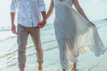 Romantic couple holding hands running and walking on beach. Man and woman in love. People travel concept.