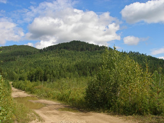 Fototapeta na wymiar Siberian forests taiga road trail/ mountains/ blue sky clouds 