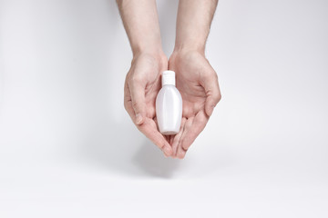 Fototapeta na wymiar a small bottle for cream, liquid or antiseptic in two hands on a white background. copyspace