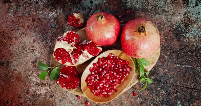 Grains of ripe pomegranate on wooden plate rotate slowly.