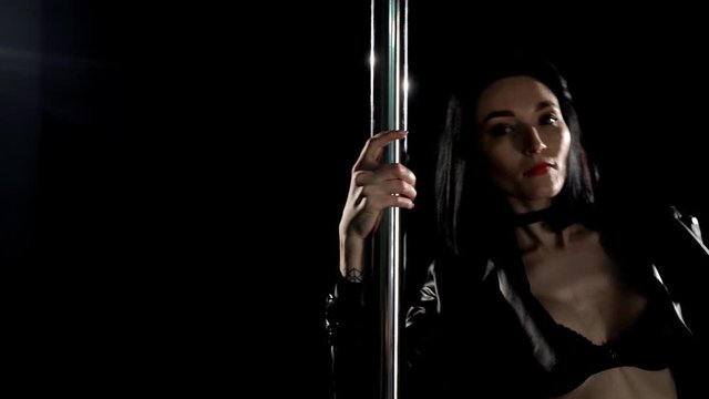 Slim woman in black lingerie dancing near pilon