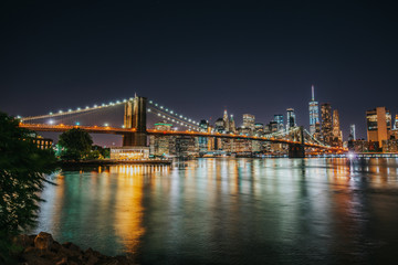 Naklejka na ściany i meble Panoramic view of Manhattan Bridge and Lower Manhattan Financial Disctrict at night with long exposure