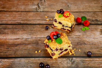 Cut blueberry sour cream cake on wooden background.