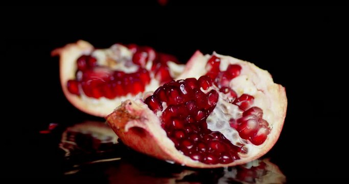 Grains of ripe pomegranate falling on the table with water.