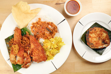 Traditional Malaysian Indian food white rice cabbage vegetable meat deep fried chopped chicken leg topped up with spicy mix gravy wood table background