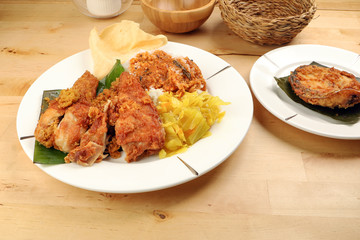 Traditional Malaysian Indian food white rice cabbage vegetable meat deep fried chopped chicken leg topped up with spicy mix gravy wood table background