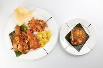 Traditional Malaysian Indian food white rice cabbage vegetable meat deep fried chopped chicken leg topped up with spicy mix gravy white background