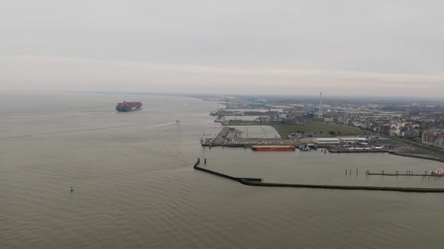 Aerial panoramic view over the Port and Seaside of Cuxhaven with a big Container Ship in the distance on the North Sea