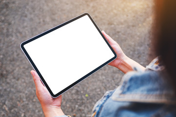 Top view mockup image of a woman holding black tablet pc with blank white screen in the outdoors...