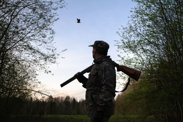 a hunter looks at a flying woodcock late at night - obrazy, fototapety, plakaty