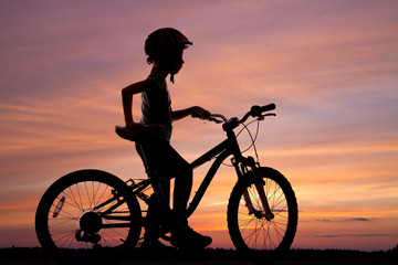Obraz premium silhouette of a girl with a bicycle on the background of the sunset