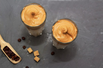 Dalgona coffee. Korean coffee in two glasses with brown sugar, coffee on  white background. Drink cold milk. Top view. Copy space