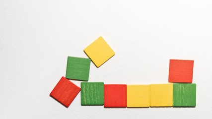 Obraz premium Different colorful squares wooden on white background. Geometric shapes red, green, yellow colors, top view. Concept of geometry. Copy space. Children educational logical task. Flat lay.