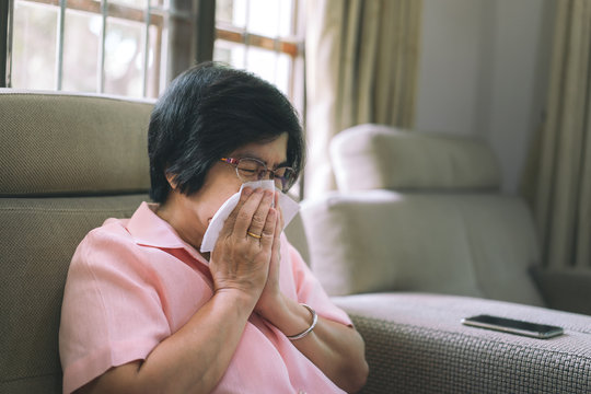 Asian elderly woman cough and sneeze in living room.